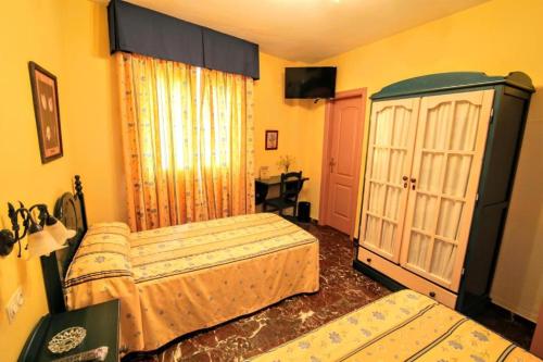 a bedroom with two beds and a cabinet and a television at Apartamentos Turísticos La Fonda in Dúrcal
