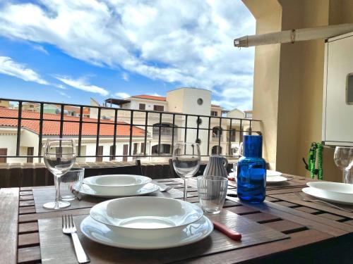 un tavolo con piatti e bicchieri da vino su un balcone di La corte di Edo a Porto Torres