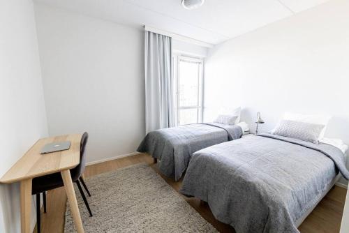 a bedroom with two beds and a desk and a window at Apartment Sleepwell, Leppävaara, 71m2 with private sauna in Espoo