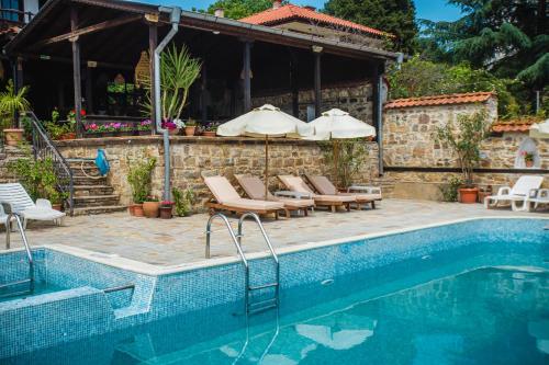 Una piscina con sillas y sombrillas al lado de una casa. en VILLA SOL, en Sunny Beach