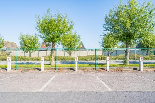 a fence in a parking lot with trees in the background at Cottage 213 in Sunparks Oostduinkerke with free parking and garden in Koksijde