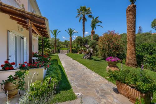 a garden of a house with flowers and palm trees at Villa Phoenix in Keri