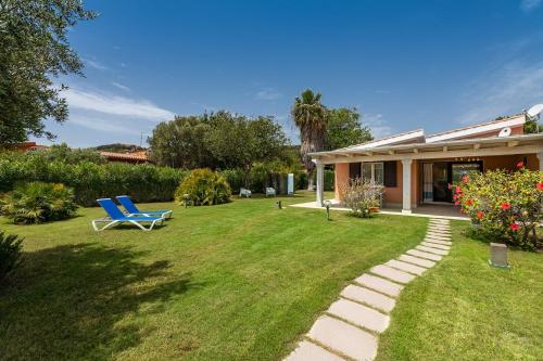 einen Garten mit einem blauen Stuhl und einem Haus in der Unterkunft Villa Zen - On the Beach in Costa Rei