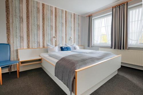 a bedroom with a large bed and a blue chair at Hotel Schiffer in Bensersiel
