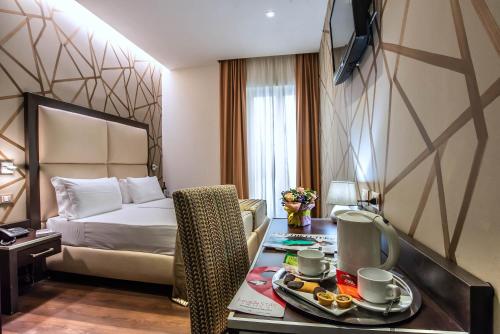 a hotel room with a bed and a table with a tray of food at Catone District Hotel in Rome