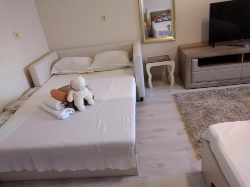 a white teddy bear sitting on a bed in a room at Къща за гости Синьо Лято in Pomorie