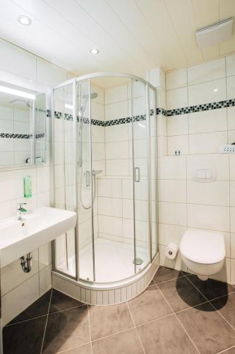 a bathroom with a shower and a sink and a toilet at Hotel Schiffer in Bensersiel