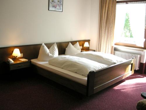 a bedroom with a bed with white sheets and pillows at Hotel Rhönhof in Oberleichtersbach