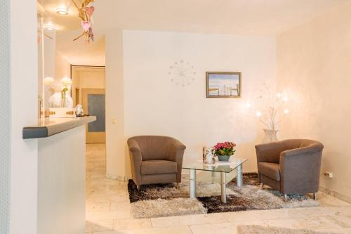 a living room with two chairs and a table at Hotel Schiffer in Bensersiel