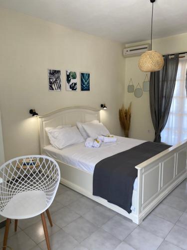 1 dormitorio con 1 cama blanca y 1 silla en Lemon Tree Apartments B C, en Argostoli