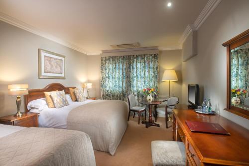 a hotel room with two beds and a desk at Killarney Lodge in Killarney
