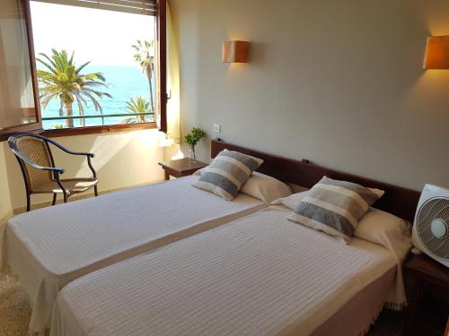 two beds in a room with a large window at Hotel Maeva ,1 star B&B in Lloret de Mar