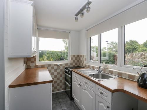 a kitchen with a sink and two windows at 40 The Ridgeway in Weymouth