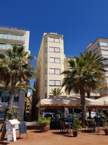 a building with palm trees and tables and chairs at Hotel Maeva ,1 star B&B in Lloret de Mar