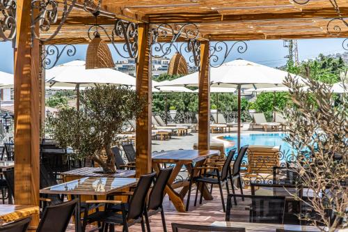 een terras met tafels en stoelen en een zwembad bij Elementa Boutique Hotel - Adults Only in Yalıkavak