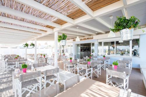 un restaurante con mesas blancas, sillas y plantas en Hotel Atlantica, en Cesenatico