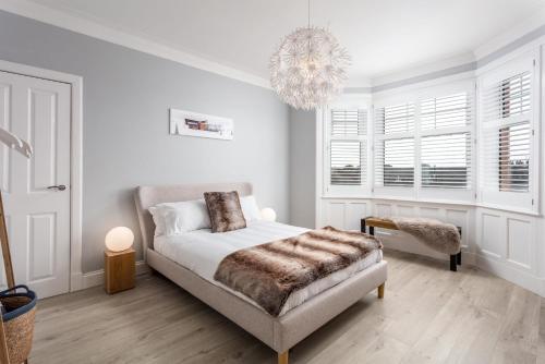 a white bedroom with a bed and a chandelier at Rothiemay House - Donnini Deluxe in Prestwick