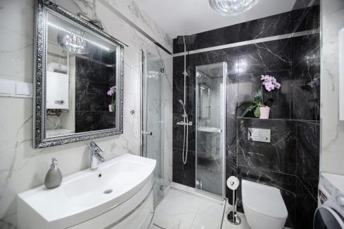 uma casa de banho em preto e branco com um lavatório e um chuveiro em Apartament Clipper em Mielno