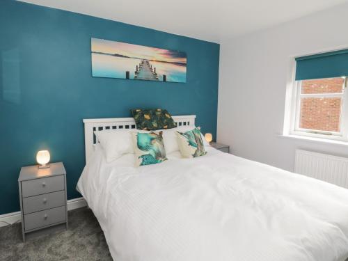 a bedroom with a white bed and a blue wall at Dabbling Ducks in Whitby