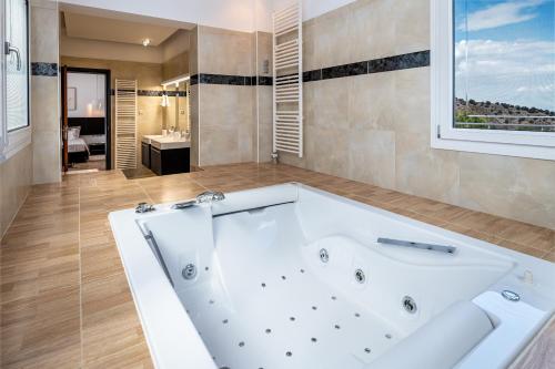 La salle de bains est pourvue d'une grande baignoire blanche et d'une fenêtre. dans l'établissement Villa Miniera, à Linopótis