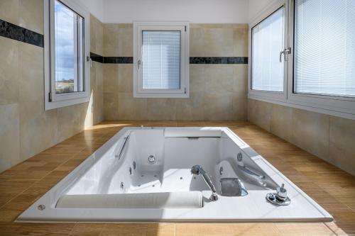 a large white bath tub in a room with windows at Villa Miniera in Linopótis