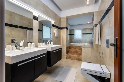 a bathroom with two sinks and a toilet and a shower at Villa Miniera in Linopótis