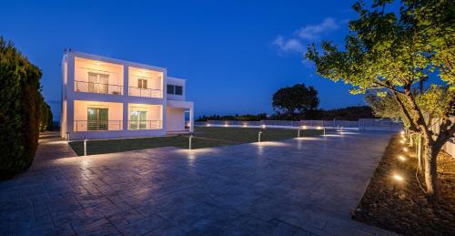 a large white building with lights in front of it at Villa Miniera in Linopótis