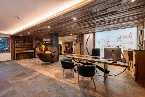 an office with a desk and chairs and a large screen at Hotel Majon Miramonti in Canazei