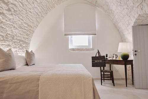 a white bedroom with a bed and a desk at 1783 Dimora d'Epoca in Locorotondo