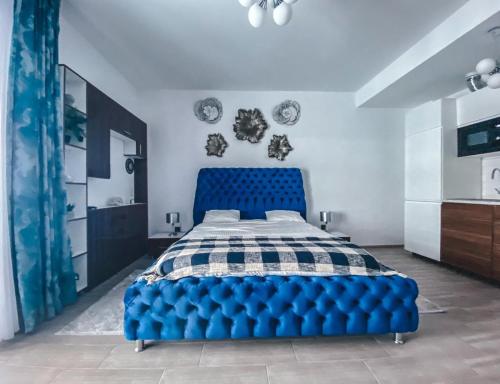 a blue tufted bed in a white bedroom at Mamaia Luxury Studio Apartment V in Mamaia