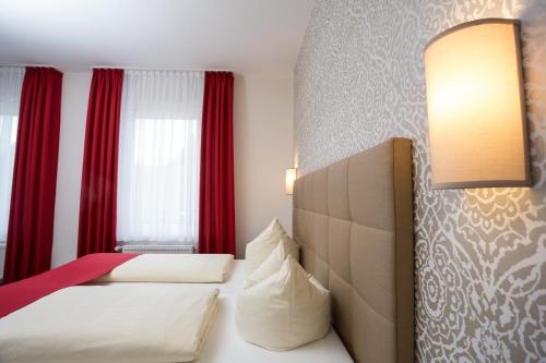 a hotel room with a bed with red curtains at Hotel Südlohner Hof - Ristorante Da Fabio in Südlohn