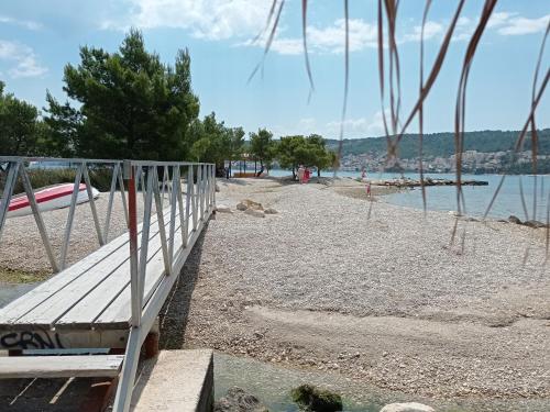 una panchina su una spiaggia accanto all'acqua di Apartmani Barišić a Trogir