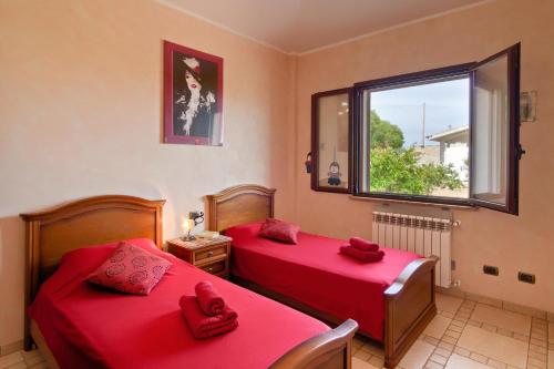 2 Betten in einem Zimmer mit roter Bettwäsche und einem Fenster in der Unterkunft Villa Limone in Gonnesa