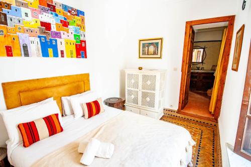 a bedroom with a bed with white sheets and red pillows at Hotel & Spa Riad Dar El Aila in Marrakech