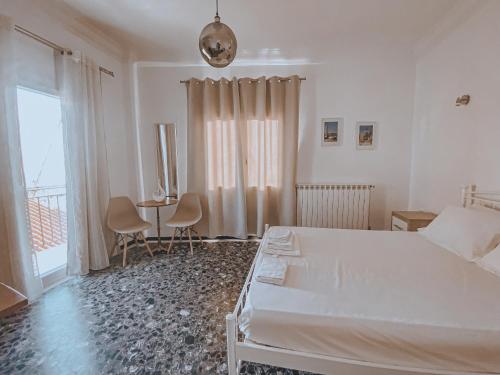 a white bedroom with a bed and a table and a window at Ether Seaside Apartment 1 in Samos