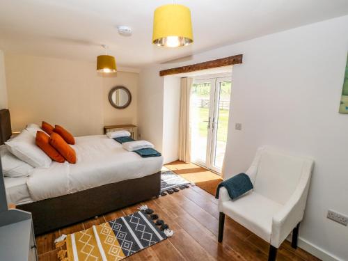 a bedroom with a bed and a chair at Y Beudy The Dairy in Oswestry