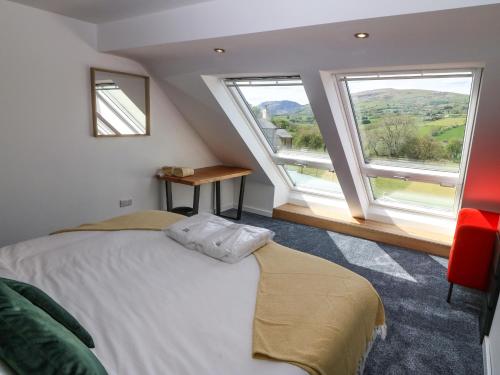 a bedroom with a bed and two large windows at Y Granar The Granary in Oswestry