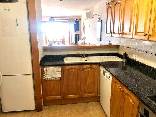 a kitchen with a sink and a white refrigerator at Balco d’es Trenc in Sa Ràpita