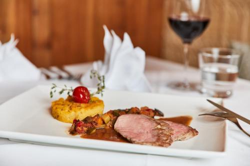 a white plate with meat and vegetables on a table at Luxury All Inclusive Resort Schwarzbrunn 4 Sterne Superior in Stans