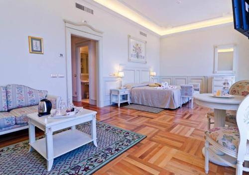a living room with two beds and two tables at Hotel De Paris Sanremo in Sanremo
