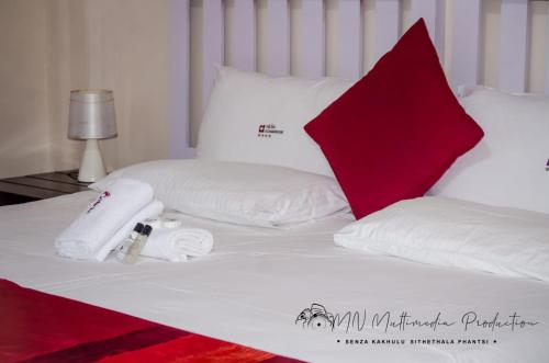 a white bed with white pillows and a red pillow at Smart Diva Accommodation in East London