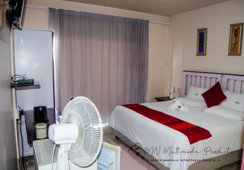 a hotel room with a bed and a fan at Smart Diva Accommodation in East London
