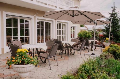 a patio with tables and chairs and an umbrella at Villa Thermale in Unterlamm