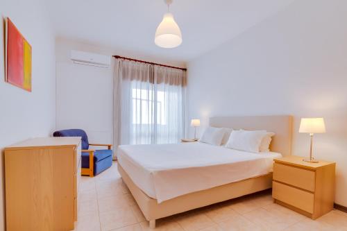 1 dormitorio con cama blanca y ventana en AL - Apartamento Infante Sagres, en Quarteira