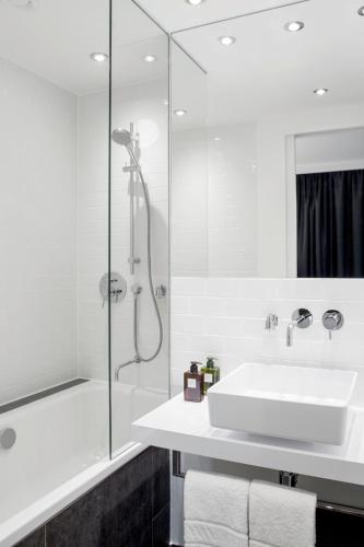a white bathroom with a sink and a shower at Hotel AMANO Grand Central in Berlin