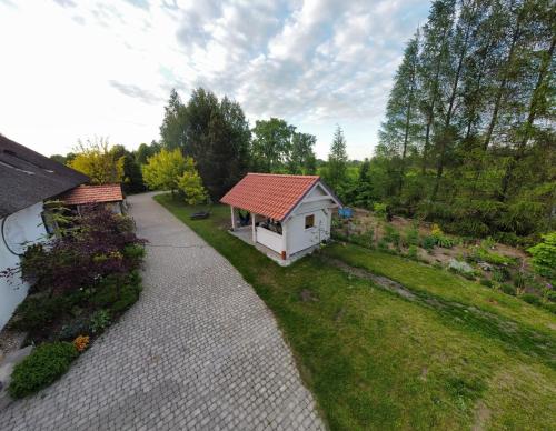 une petite maison blanche avec un toit rouge dans une cour dans l'établissement KRASNE POLE Gospodarstwo Rolne, à Krasnopol