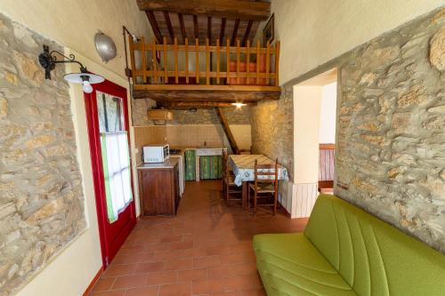 salon z zieloną kanapą i kamienną ścianą w obiekcie Agriturismo Podere Carducci w mieście Castagneto Carducci