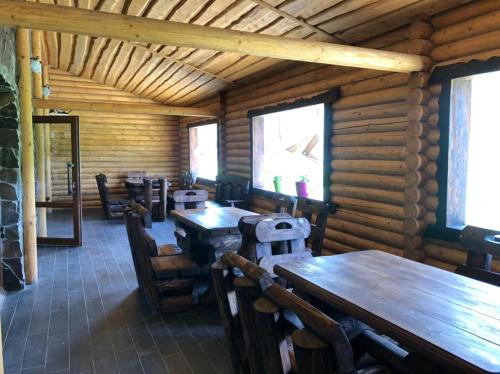 a dining room with tables and chairs in a log cabin at Шервуд in Myta