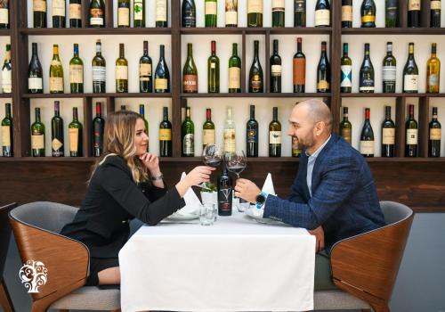 a man and woman sitting at a table with wine glasses at Agape Villa Apartments in Novi Sad