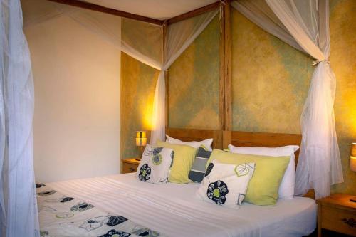 a bedroom with a canopy bed with green and white pillows at Casa Mara Dakar in Dakar